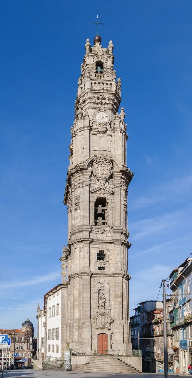 Torre dos Clérigos, no Porto, torre barroca de granito vista de baixo, sob céu azul.