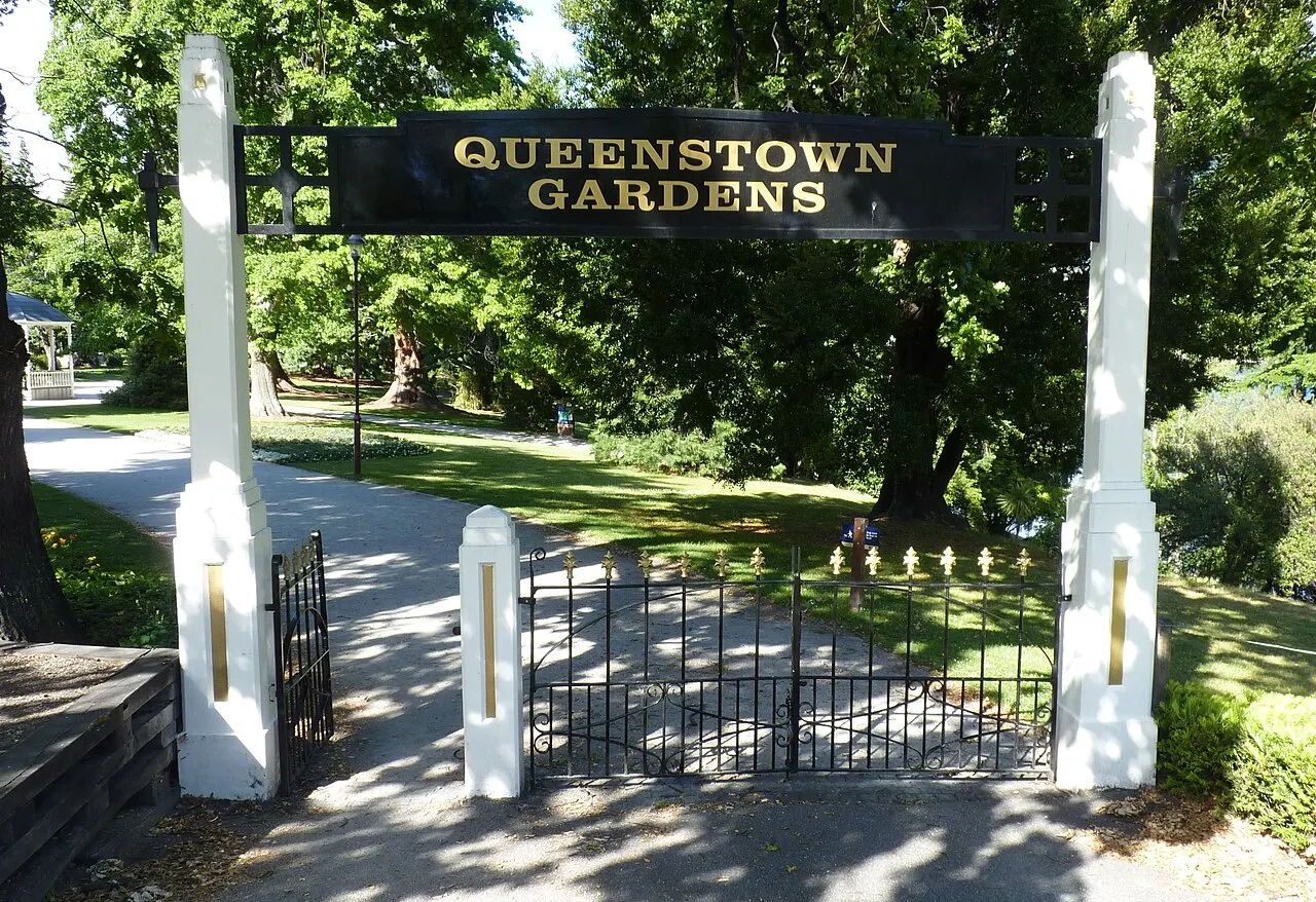 O portal de entrada dos Queenstown Gardens, com o letreiro entre dois pilares brancos.