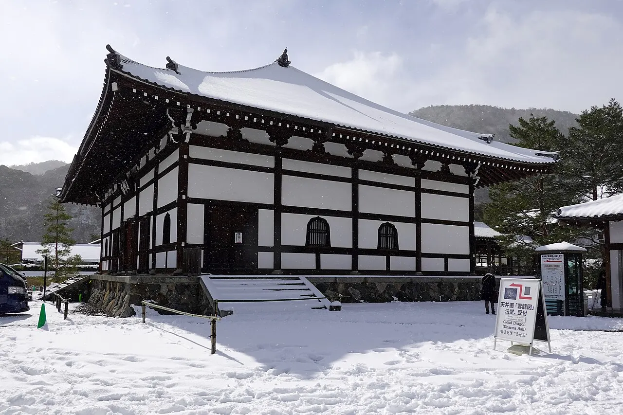 Salão de paredes brancas e vigas escuras com telhado coberto de neve.