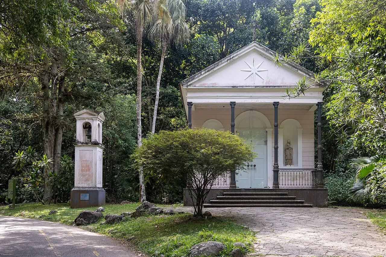 Capela branca de frontão triangular entre árvores no Parque Nacional da Tijuca, no Rio de Janeiro.