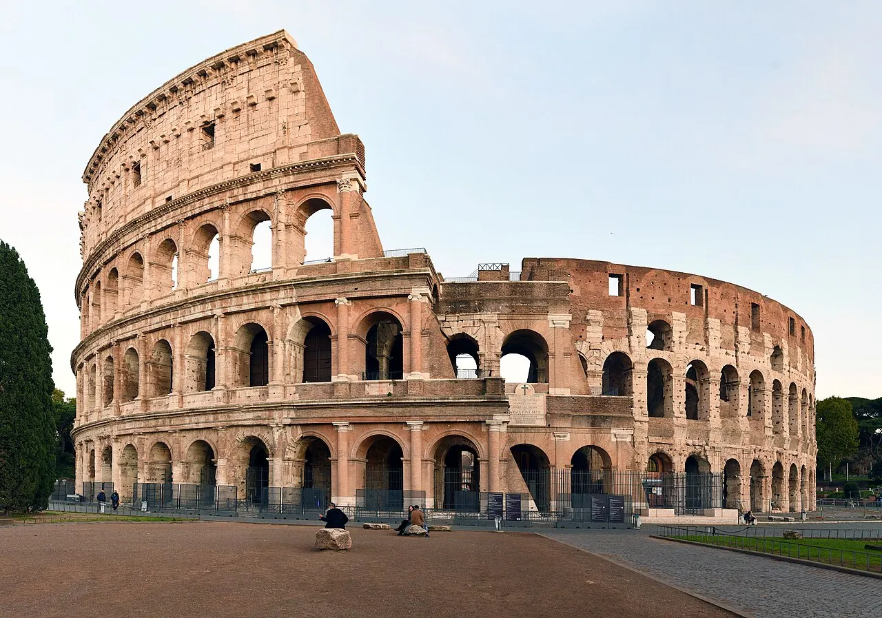Coliseu de Roma, com os três andares de arcos e o anel externo incompleto, ao entardecer.