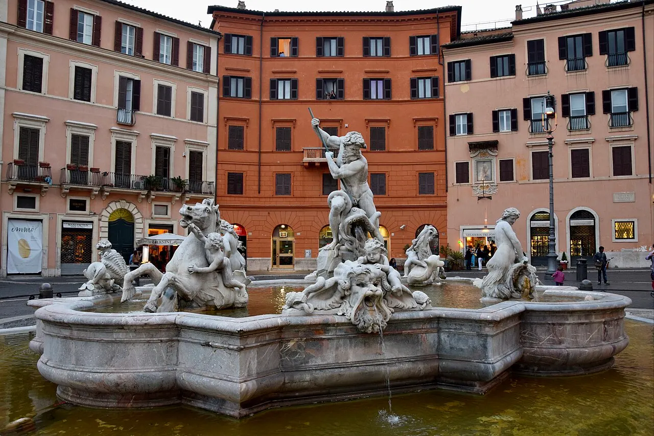 Fonte de Netuno, na Piazza Navona, em Roma, com as estátuas de mármore e as fachadas coloridas atrás.