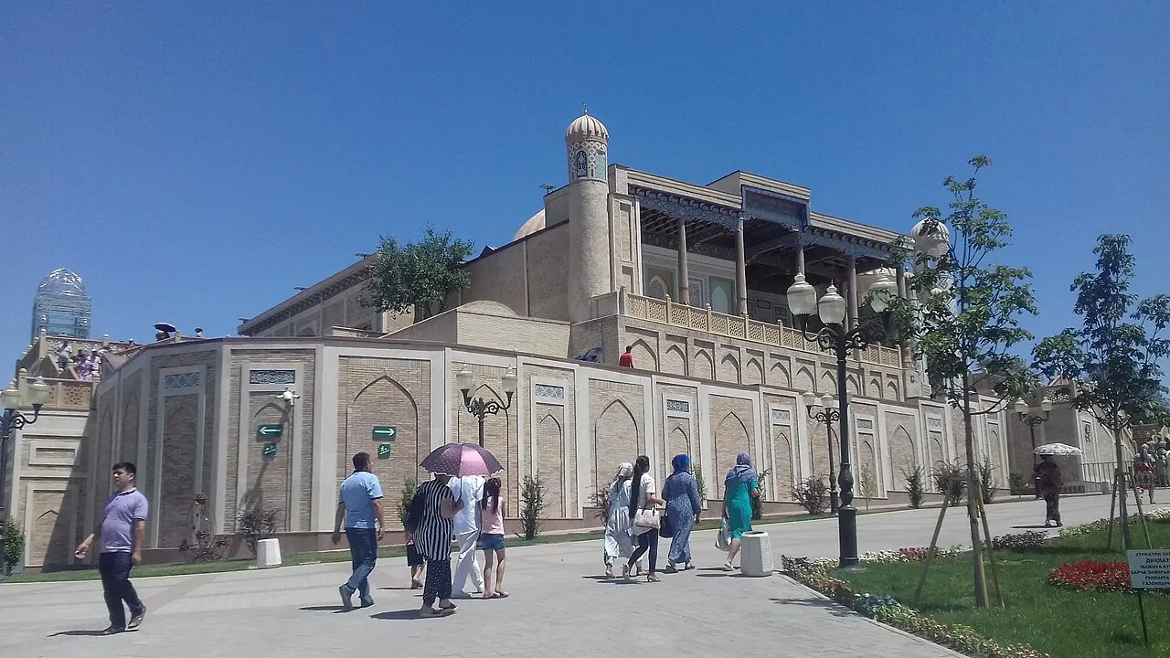 Mesquita Hazrat Khizr, em Samarcanda, com varanda de colunas de madeira, e visitantes na calçada em frente.