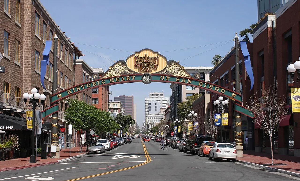 Arco ornamentado com letreiro «Gaslamp Quarter» sobre uma rua de prédios de tijolo e postes antigos