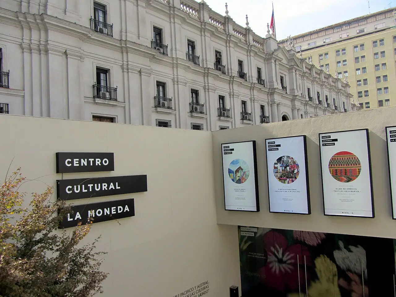 Entrada do Centro Cultural La Moneda, com o letreiro na parede e a fachada branca do palácio acima.