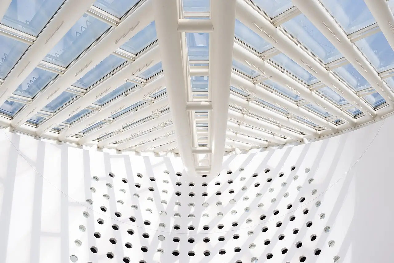 Teto do SFMOMA, com claraboias em grade e uma parede curva branca cheia de furos redondos.