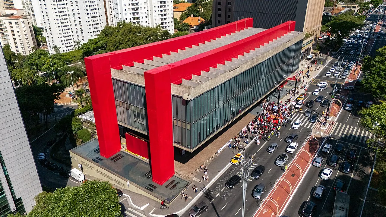 MASP, na Avenida Paulista, com o volume envidraçado suspenso entre os pilares vermelhos, visto do alto.