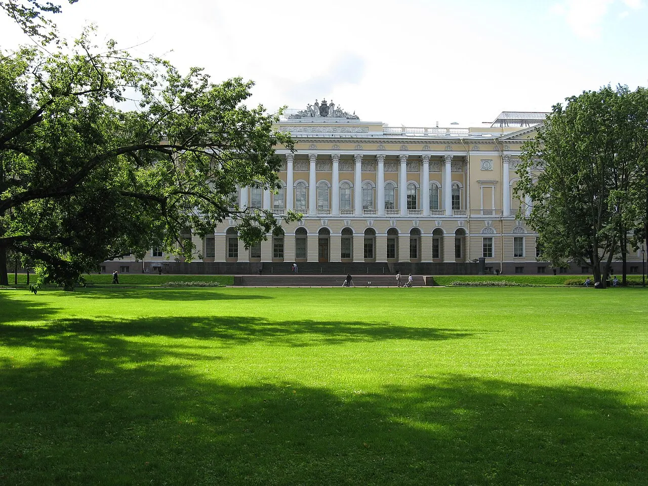 Palácio Mikhailovsky, sede do Museu Russo, em São Petersburgo, visto do gramado do jardim, entre árvores.