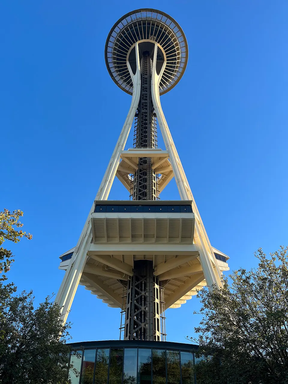 La Space Needle, à Seattle, avec sa soucoupe sur trois piliers, vue d'en bas sous un ciel bleu.