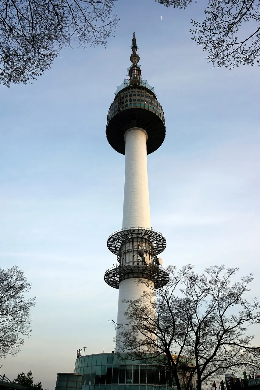 Torre branca e fina com observatório escuro no alto, contra o céu claro.