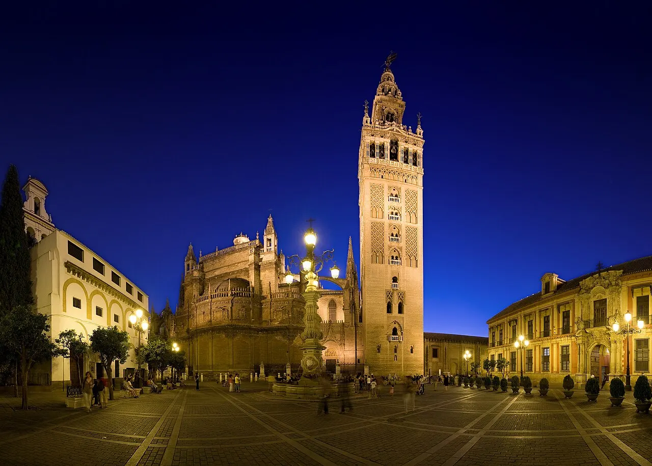 Giralda e parte da Catedral de Sevilha iluminadas ao entardecer, vistas da Plaza Virgen de los Reyes.