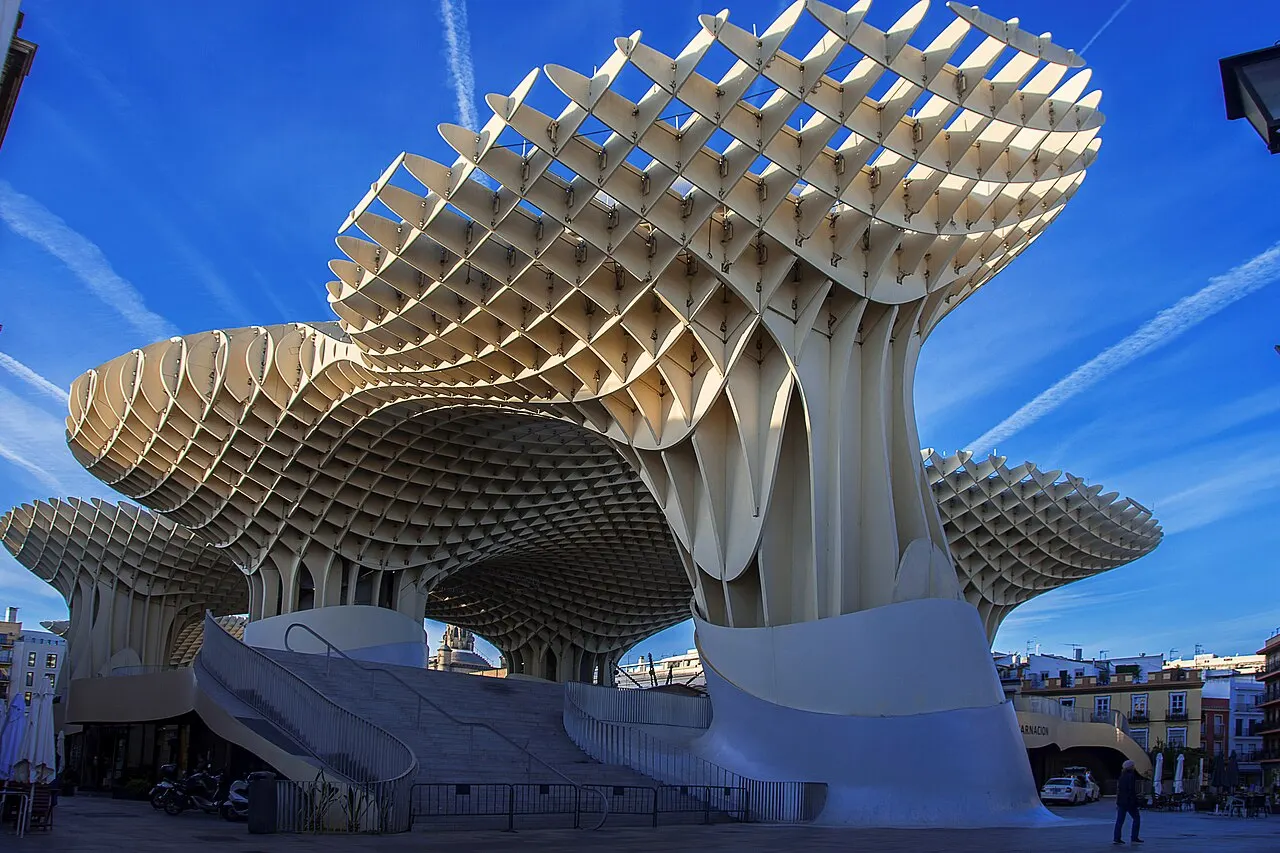 A estrutura de madeira do Metropol Parasol, com cobertura em formas de cogumelo, vista de baixo sob céu azul.