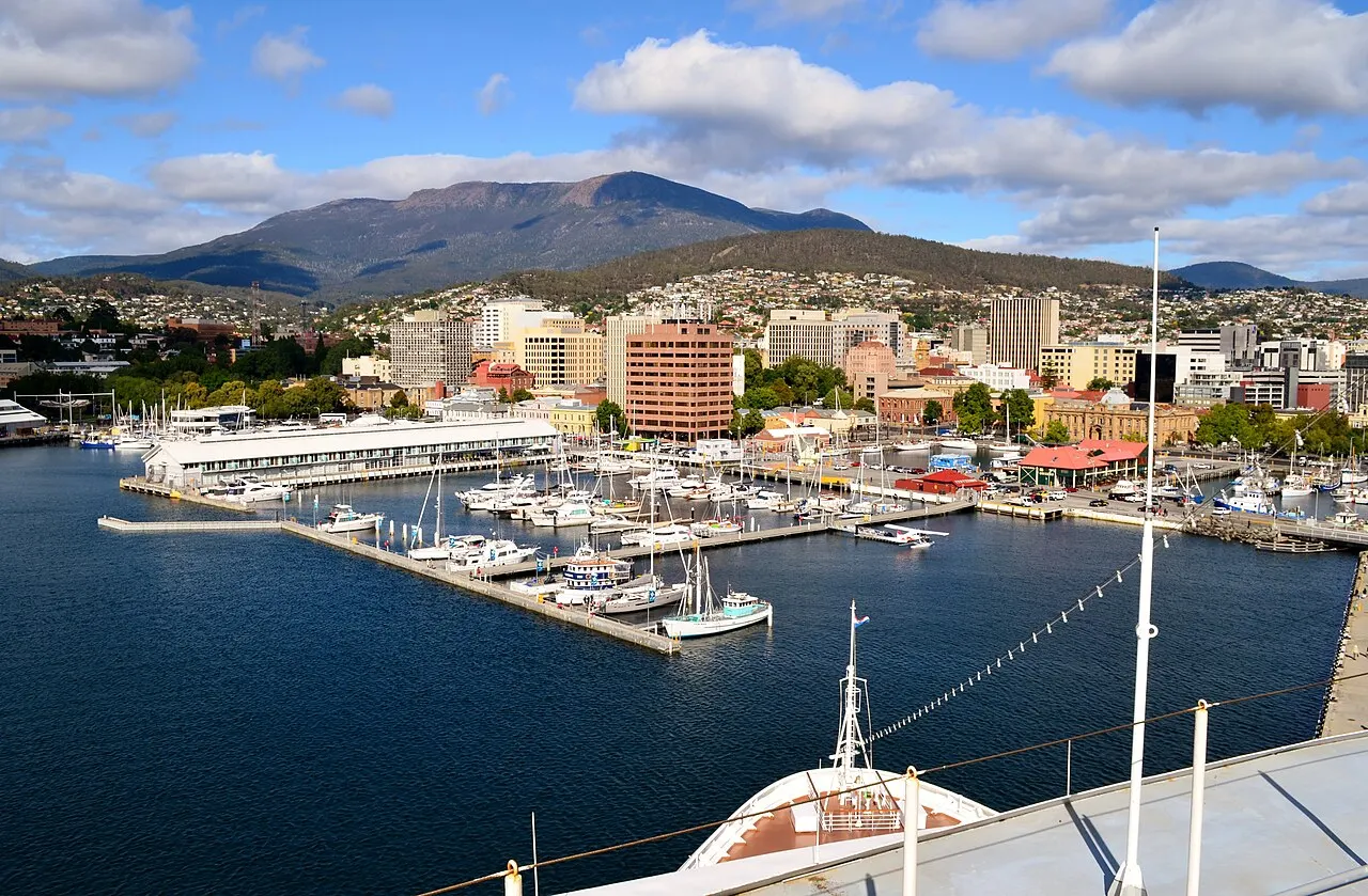 kunanyi / Mount Wellington in the background, rising above the buildings of Hobart and the Sullivans Cove marina, seen from high on a ship in port.