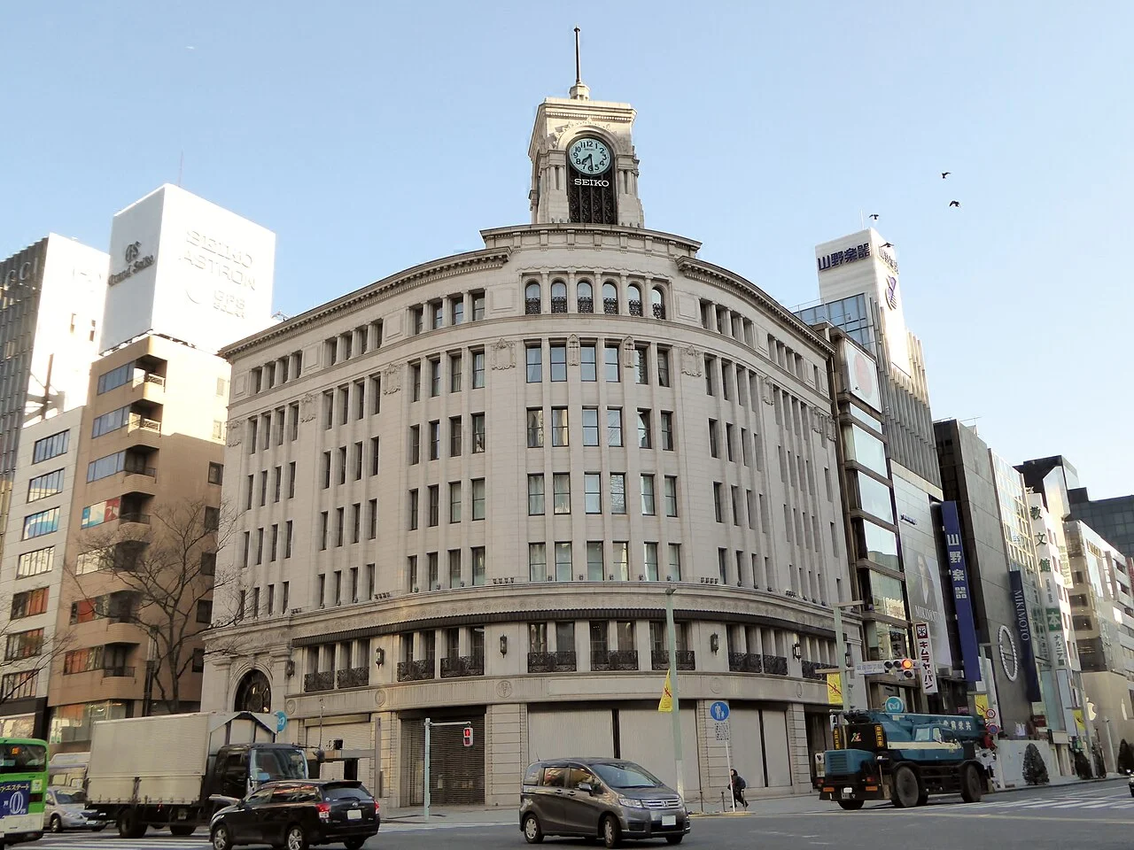 Edifício Wako com as duas terminações laterais da fachada e a antena inteira; a base tem oclusões reais por veículos, mantidas sem reconstrução.