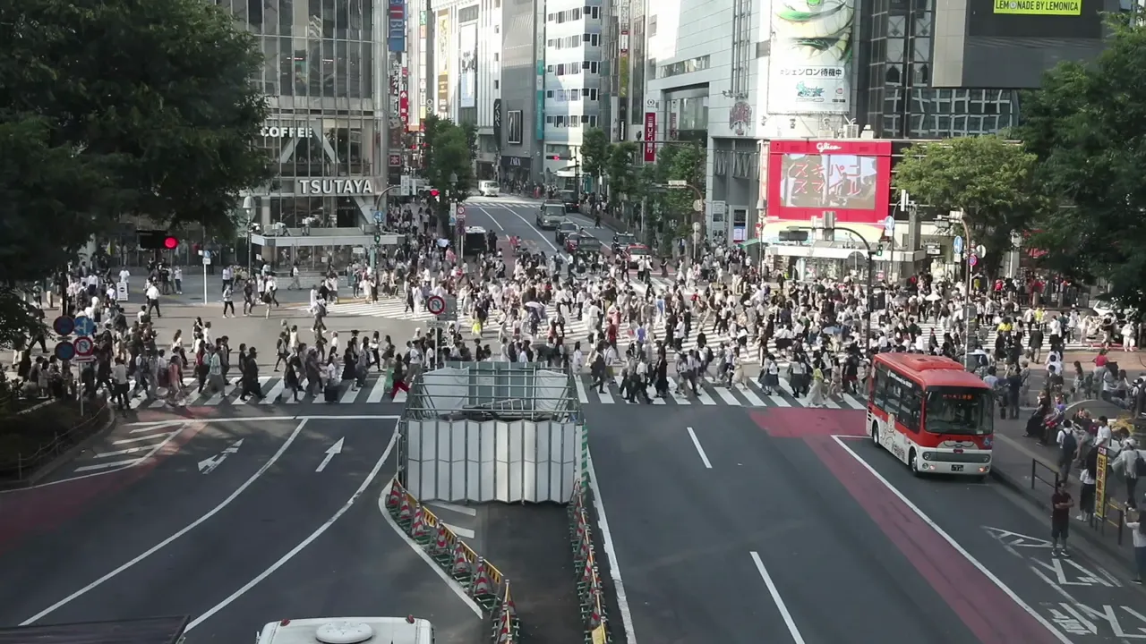 Pedestres cruzando as faixas de Shibuya vistos do alto.