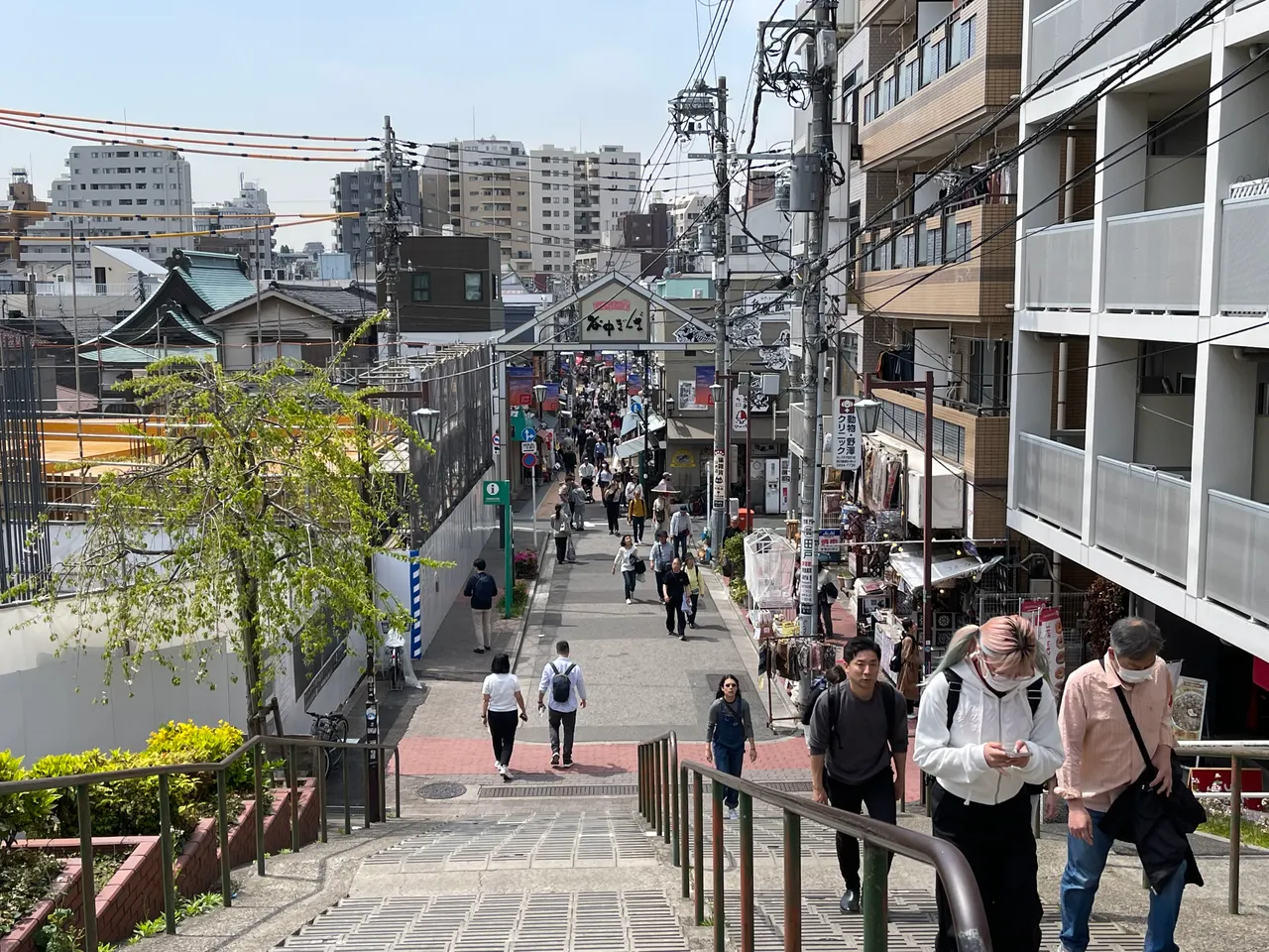 Escadaria descendo para uma rua comercial estreita com pedestres.