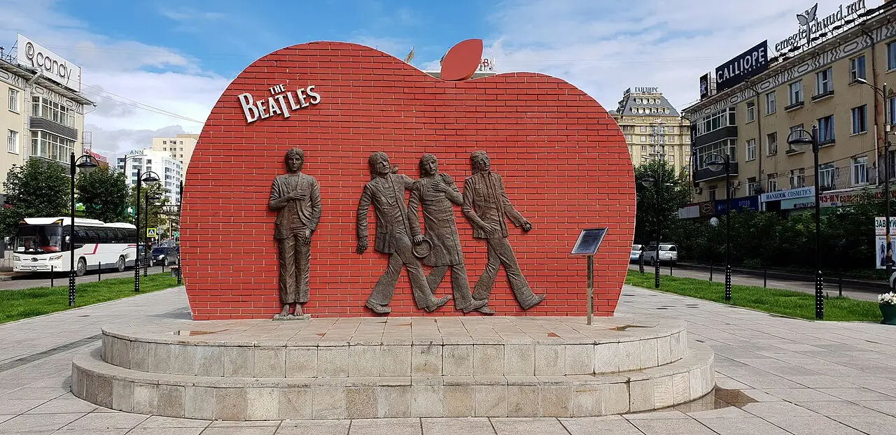 Monumento aos Beatles, maçã de tijolo com o nome e quatro figuras de bronze caminhando.