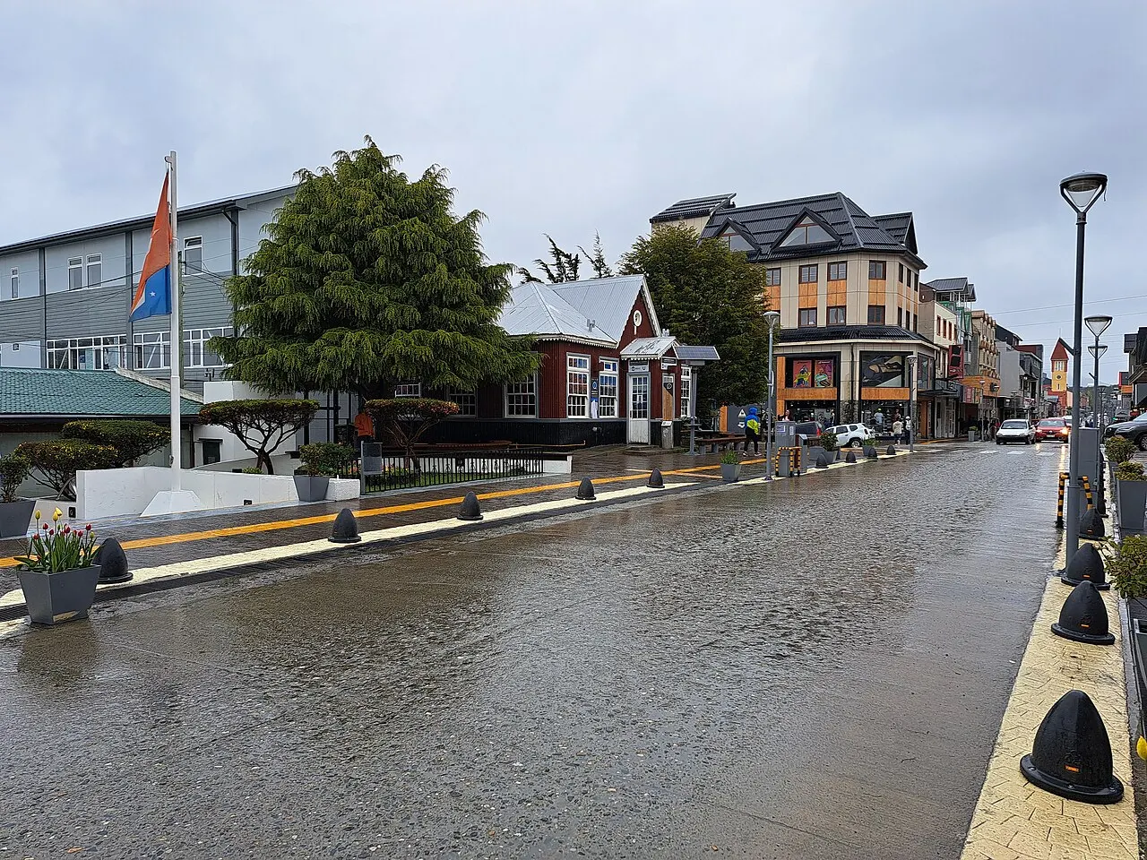 A Avenida San Martín, larga e com o asfalto molhado, com casas e prédios baixos dos dois lados sob céu nublado.