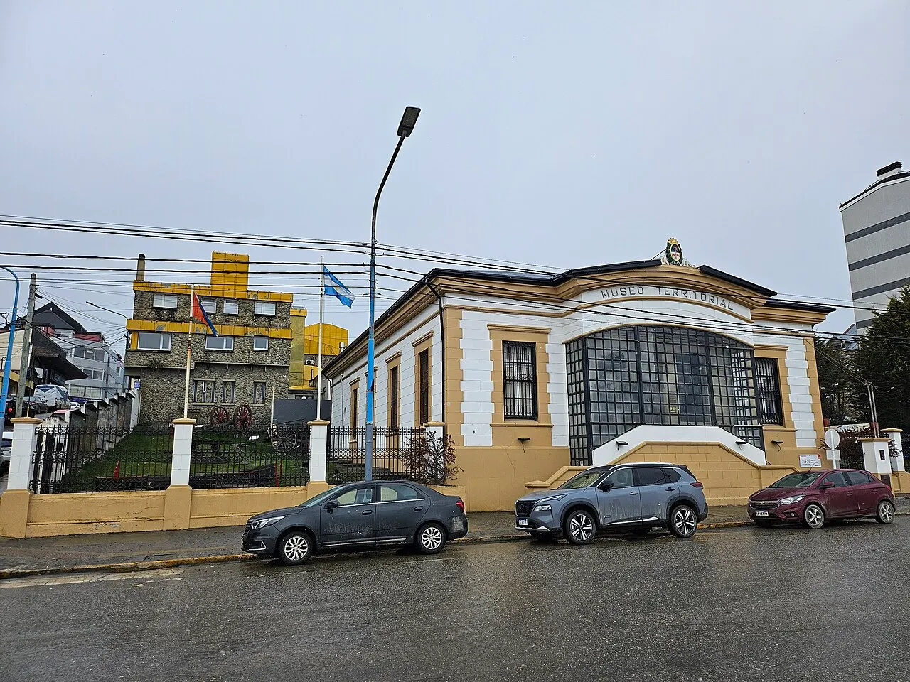 A casa histórica do Museo del Fin del Mundo, com carros estacionados na frente.