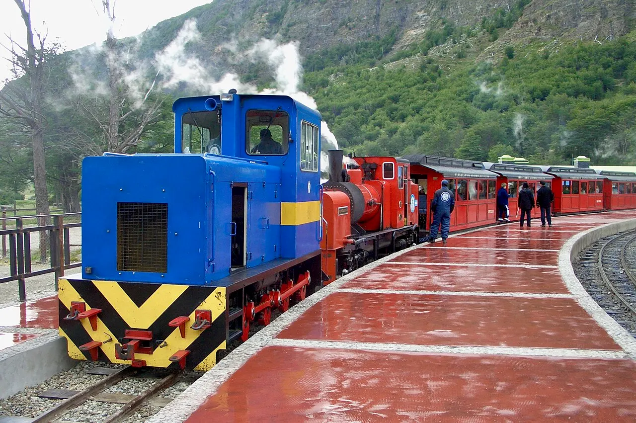 A composição do Tren del Fin del Mundo parada na estação, em dia de chuva.