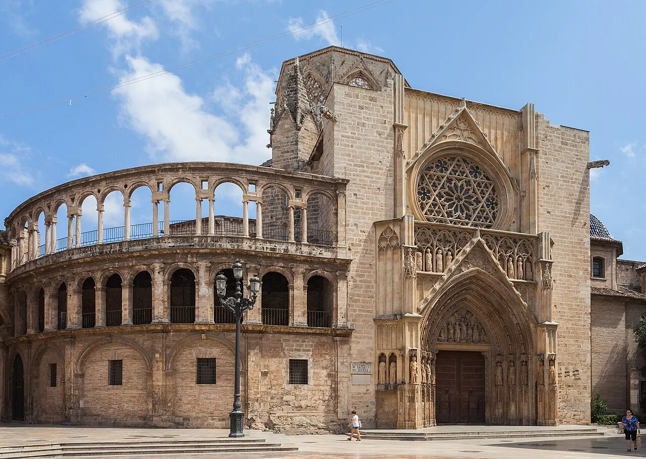 A Catedral de Valência vista da praça: a galeria de arcos da abside à esquerda e o portal gótico com rosácea à direita.