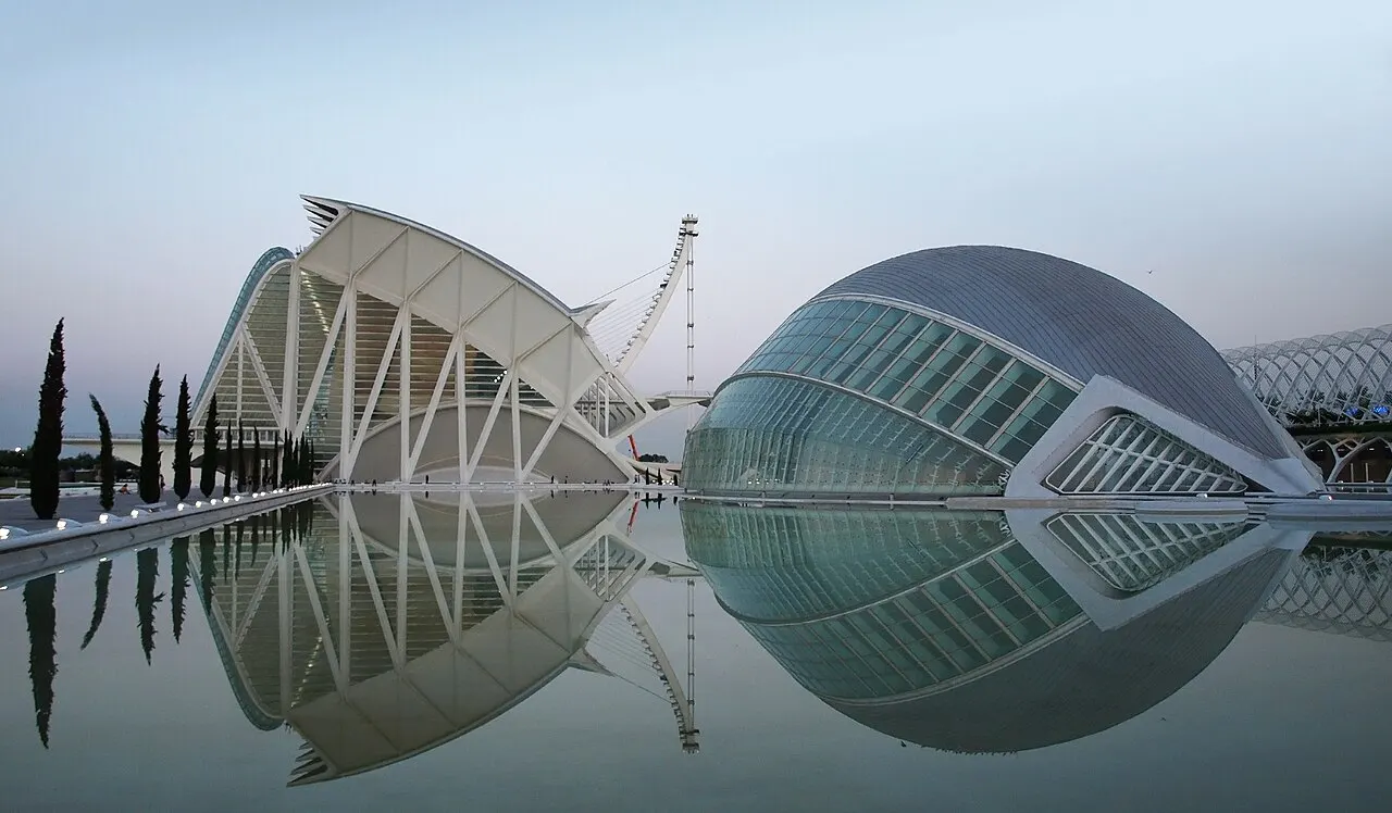 As estruturas brancas e curvas do Museu das Ciências e do Hemisfèric, na Ciudad de las Artes y las Ciencias, refletidas no espelho d'água.