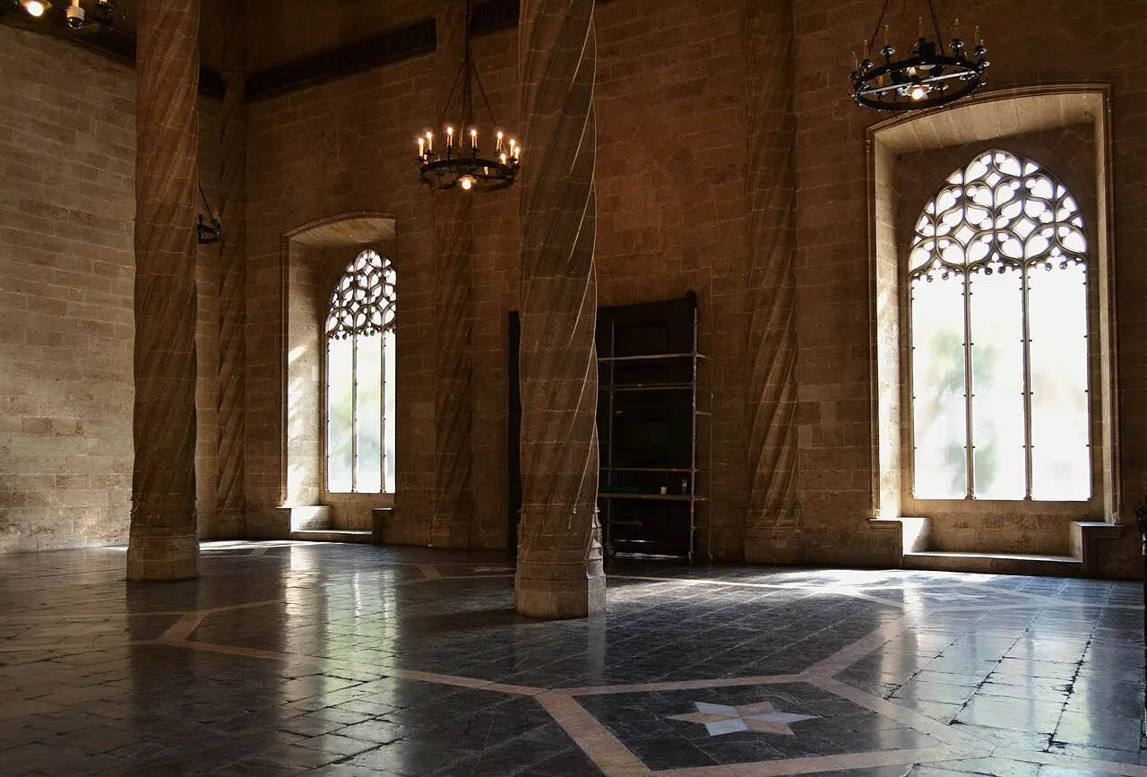 A sala de contratação da Lonja de la Seda, com colunas helicoidais, janelas góticas rendilhadas e lustres sobre o piso de mármore.