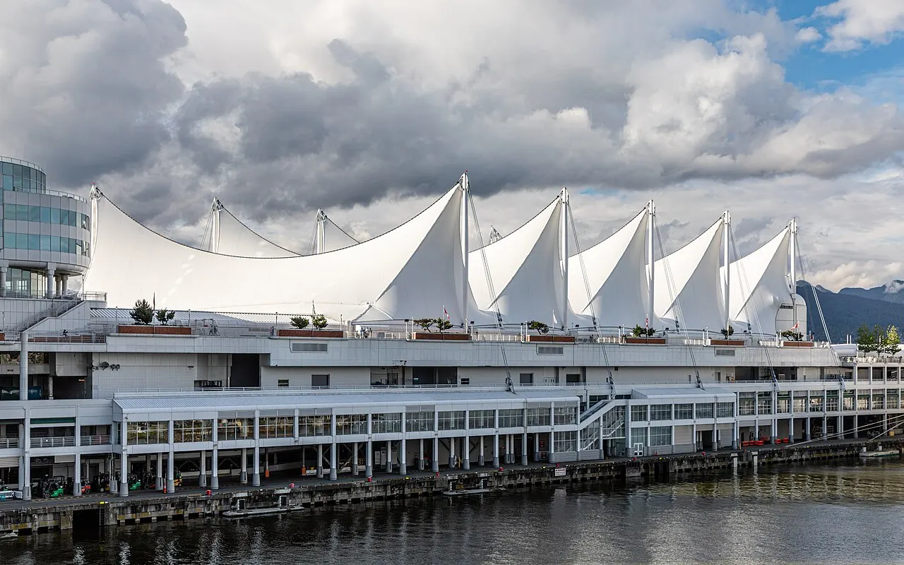 Canada Place, com sua cobertura de velas brancas sobre o cais, vista da água sob céu com nuvens.