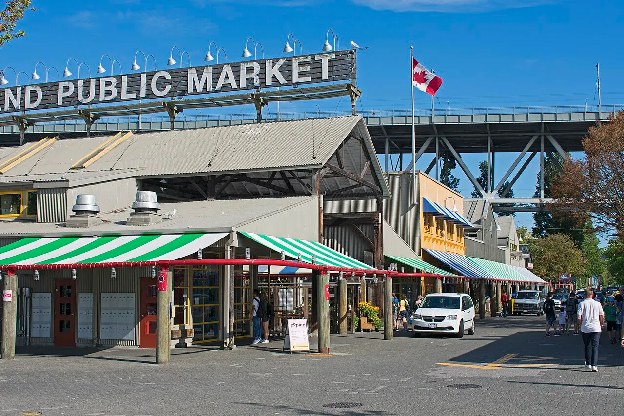 Entrada do Granville Island Public Market, com letreiro no alto, toldos listrados e pessoas na calçada.