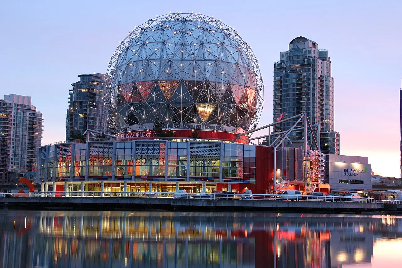 Cúpula geodésica do Science World, em Vancouver, iluminada ao entardecer, refletida na água.
