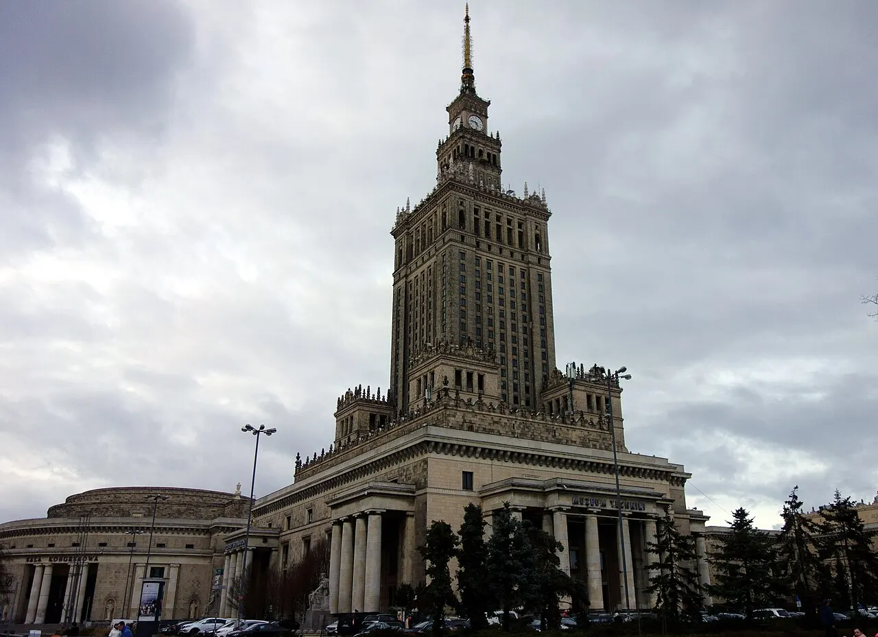 Palácio da Cultura e Ciência, em Varsóvia, com a torre em degraus e a agulha, sob céu nublado.
