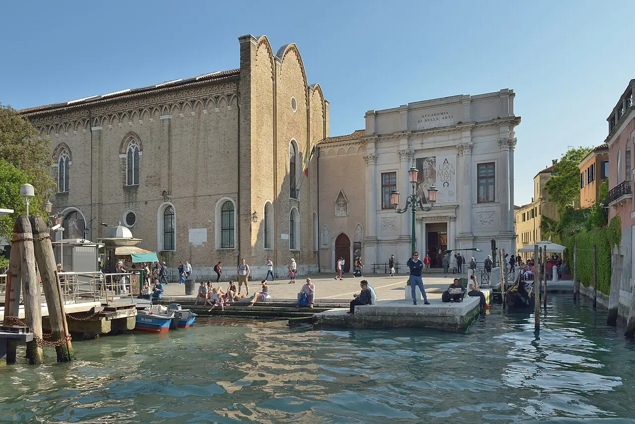 Fachadas de tijolo e pedra das Gallerie dell’Accademia, diante de um canal com barcos.