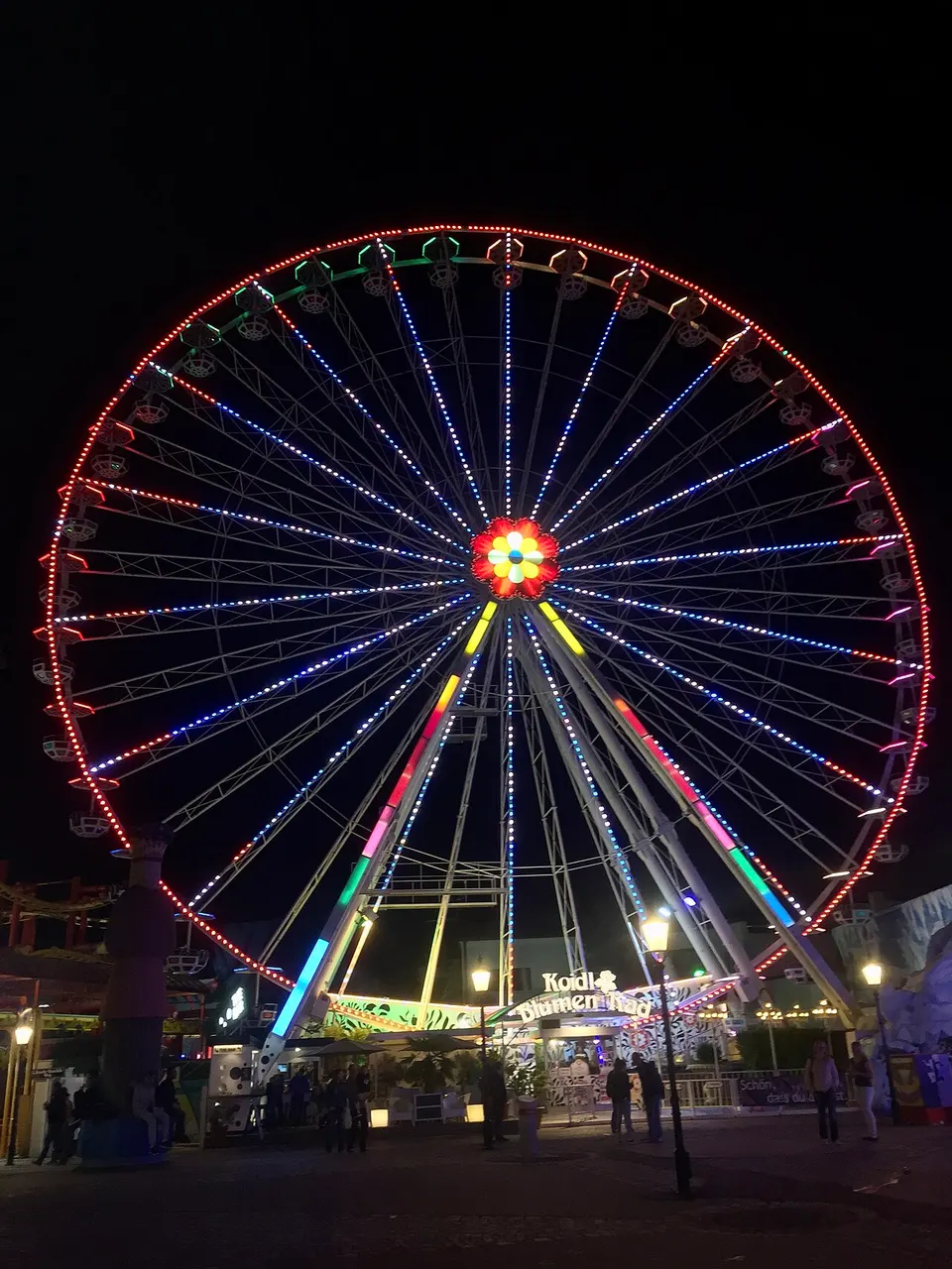 Roda-gigante iluminada em cores no parque de diversões do Prater, em Viena, à noite.