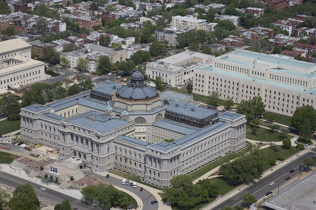 Vista aérea do edifício Thomas Jefferson da Biblioteca do Congresso: bloco de granito claro em torno de pátios, com telhados de cobre esverdeado e uma cúpula escura ao centro.