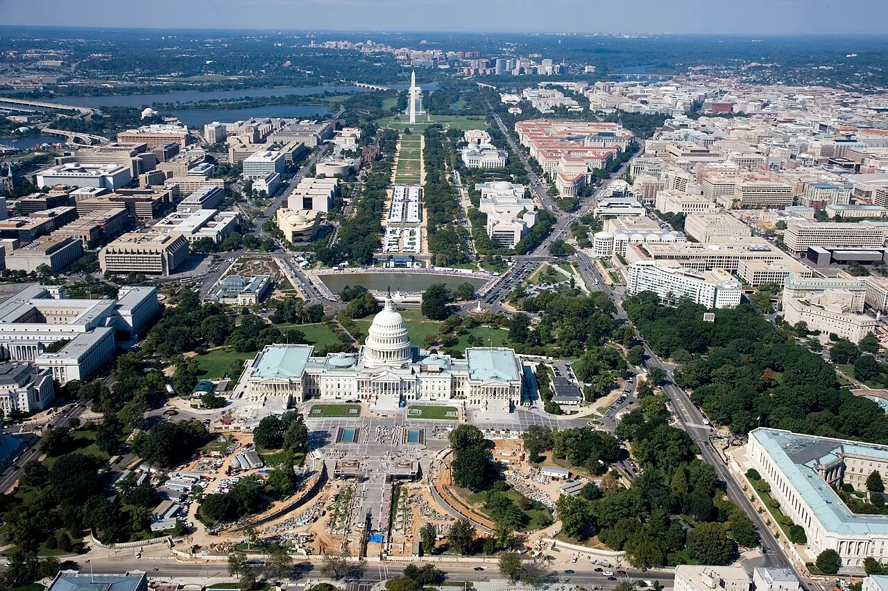 Vista aérea do National Mall, com o Capitólio dos Estados Unidos em primeiro plano, o gramado extenso e o Monumento a Washington ao fundo.