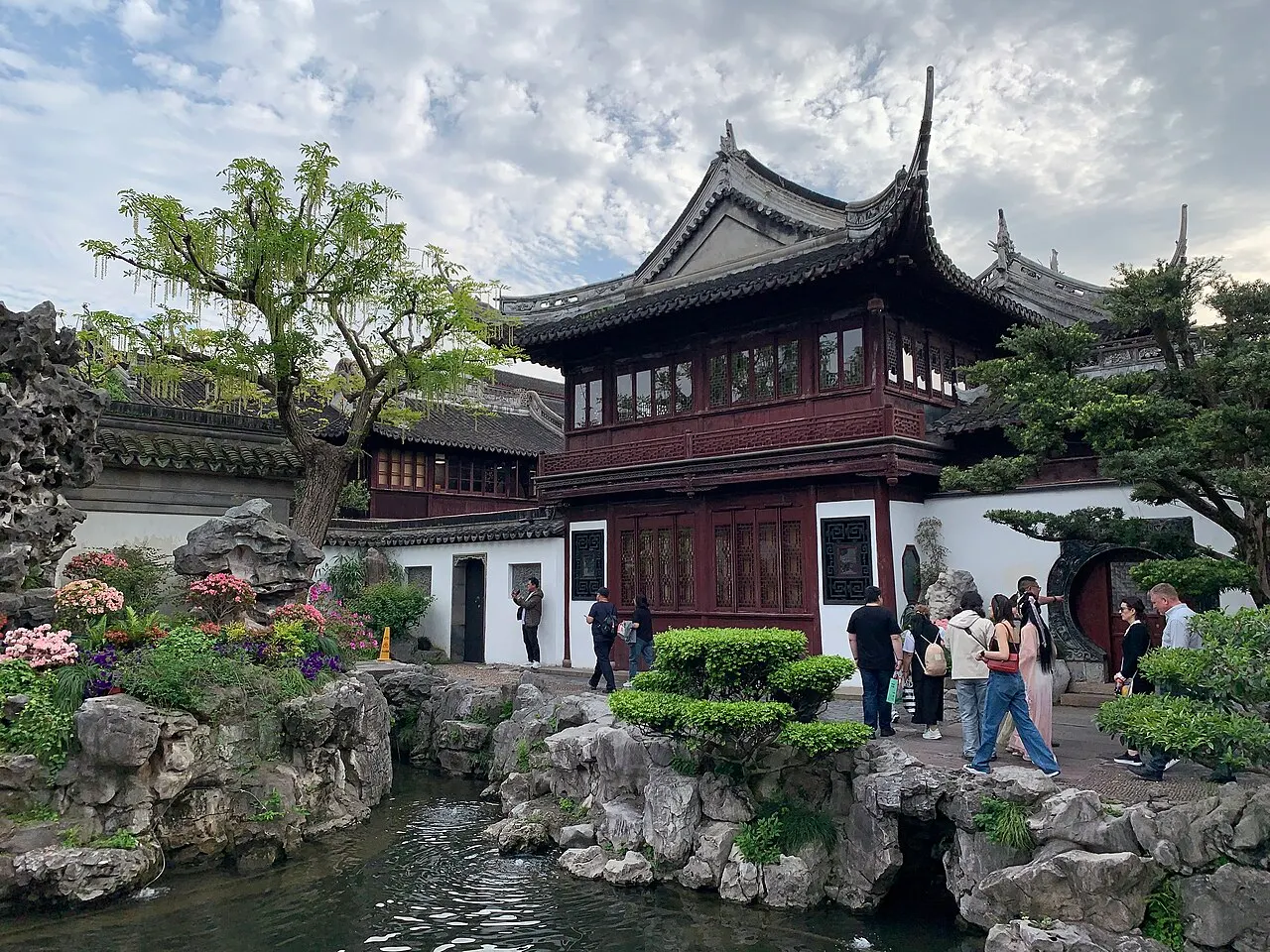 Pavilhão chinês de dois andares com telhados curvos escuros e varandas de madeira vermelha.
