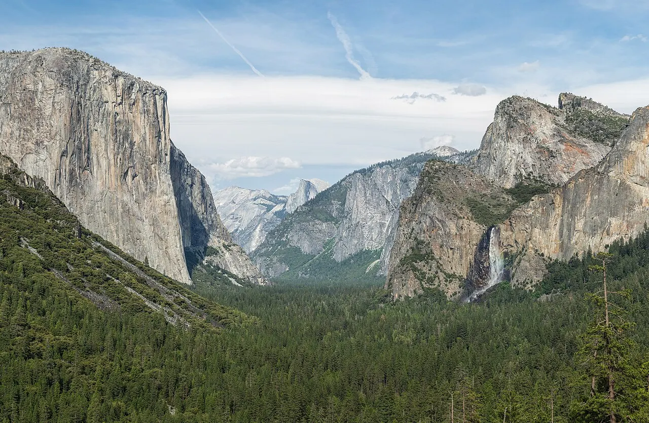 O vale de Yosemite visto do alto: o paredão de El Capitan à esquerda, a cachoeira Bridalveil à direita e a floresta cobrindo o fundo do vale.