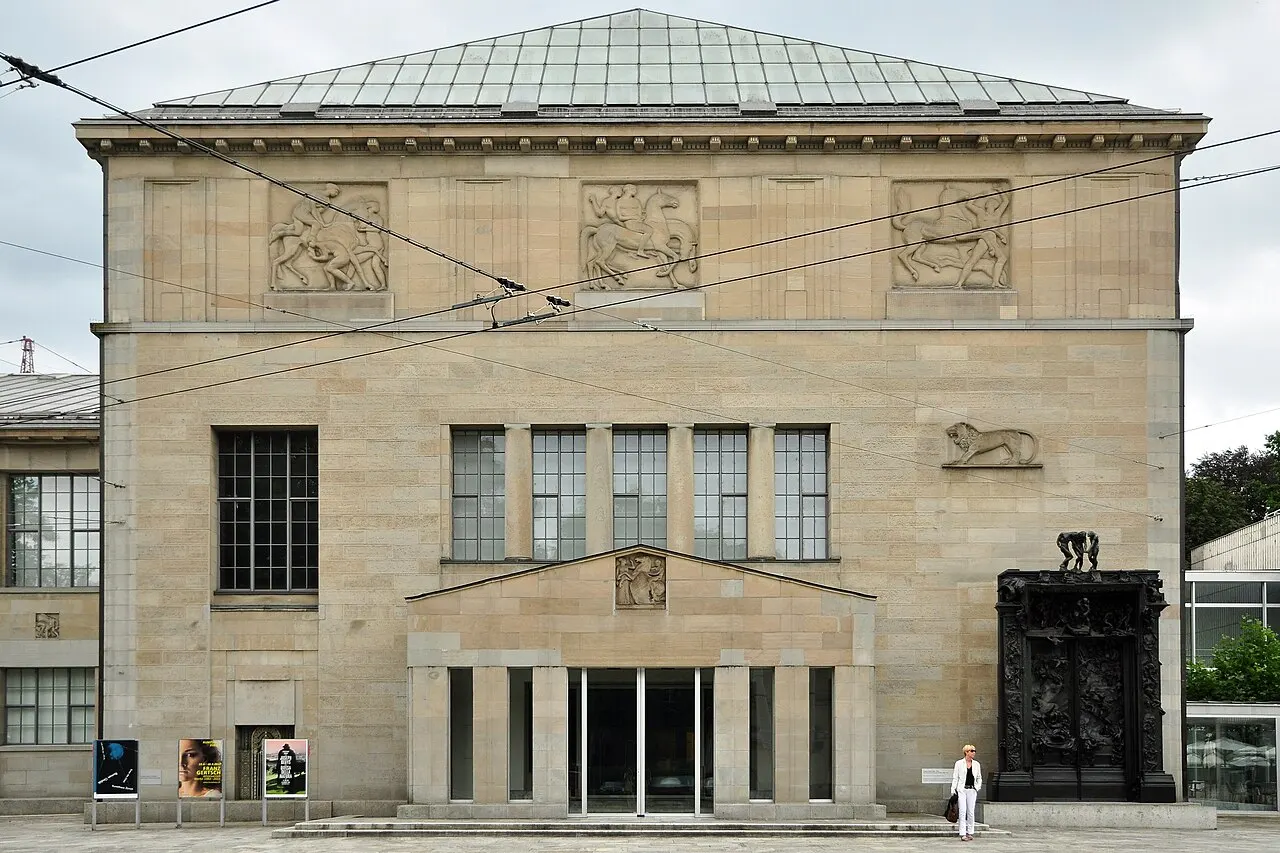 Fachada de pedra clara do Kunsthaus Zürich, com relevos no alto e entrada baixa sob o telhado em pirâmide.