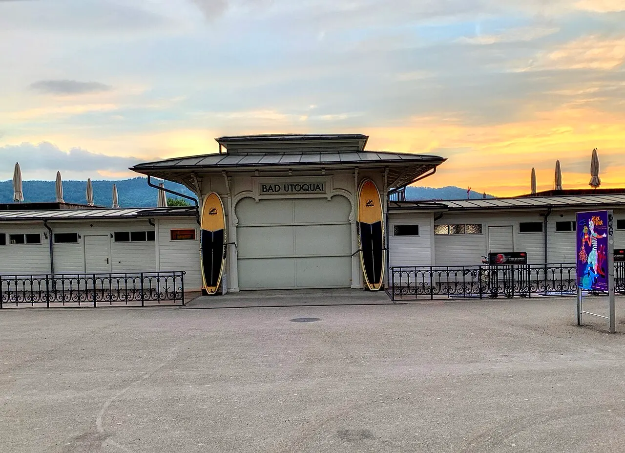 Pavilhão de entrada do Seebad Utoquai, em Zurique, com o letreiro Bad Utoquai, ao entardecer.