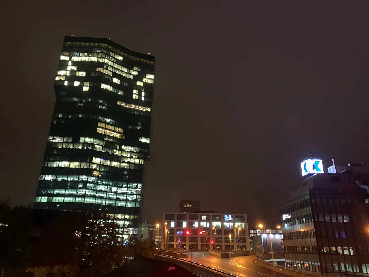A Prime Tower iluminada à noite, com edifícios do bairro de Zürich West e a região da Hardbrücke ao redor.