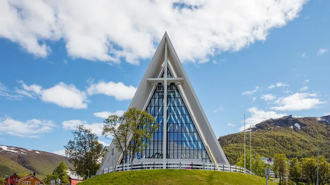 Catedral do Ártico, em Tromsø, com a fachada triangular de vidro e concreto sob céu com nuvens.