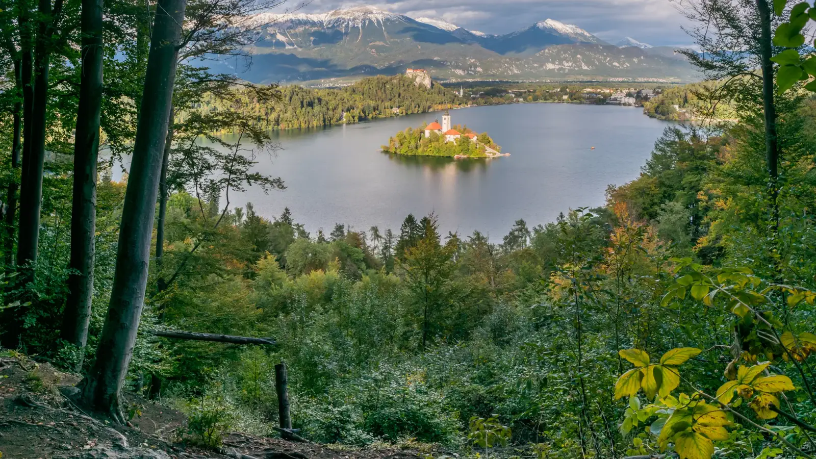 Ilha de Bled e sua igreja no lago, entre colinas.