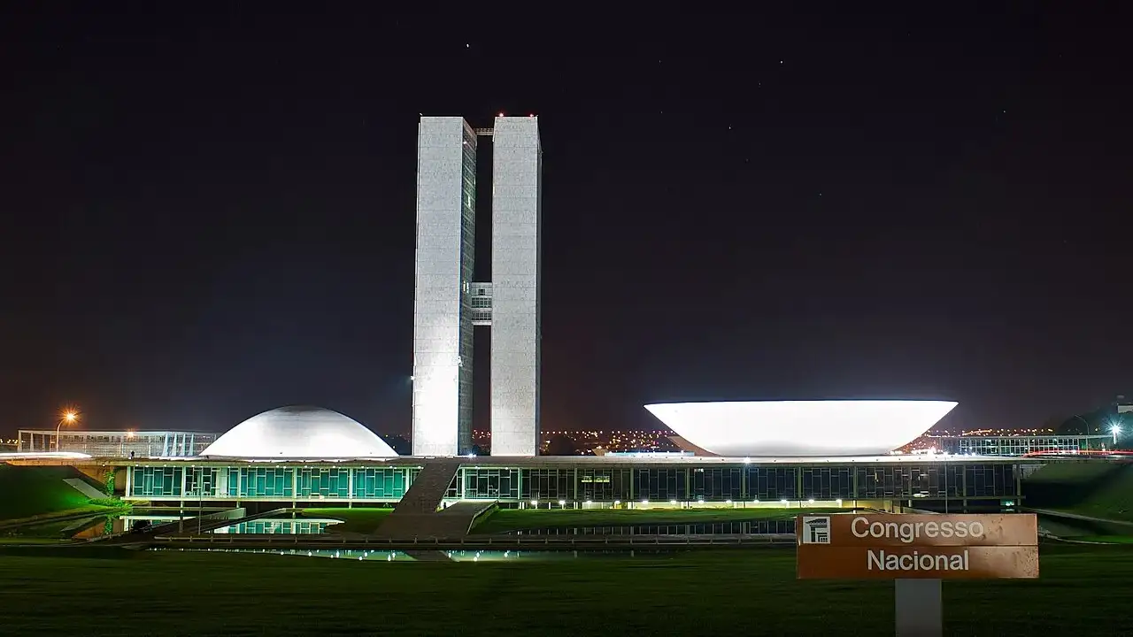 Torres gêmeas do Congresso Nacional, em Brasília, com as cúpulas do plenário ao lado, iluminadas à noite.