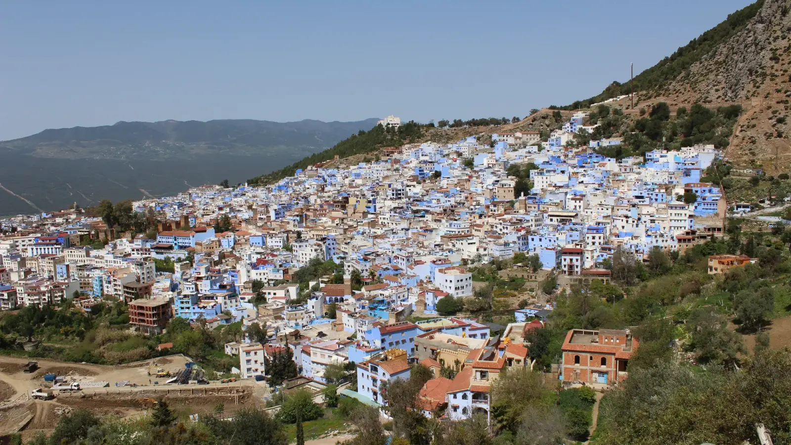 La médina bleue et blanche de Chefchaouen à flanc de colline, vue depuis la colline de la mosquée espagnole, avec les montagnes du Rif au fond