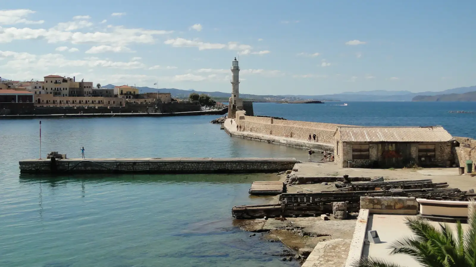Farol de Chania inteiro sobre o molhe, com o porto e o mar.