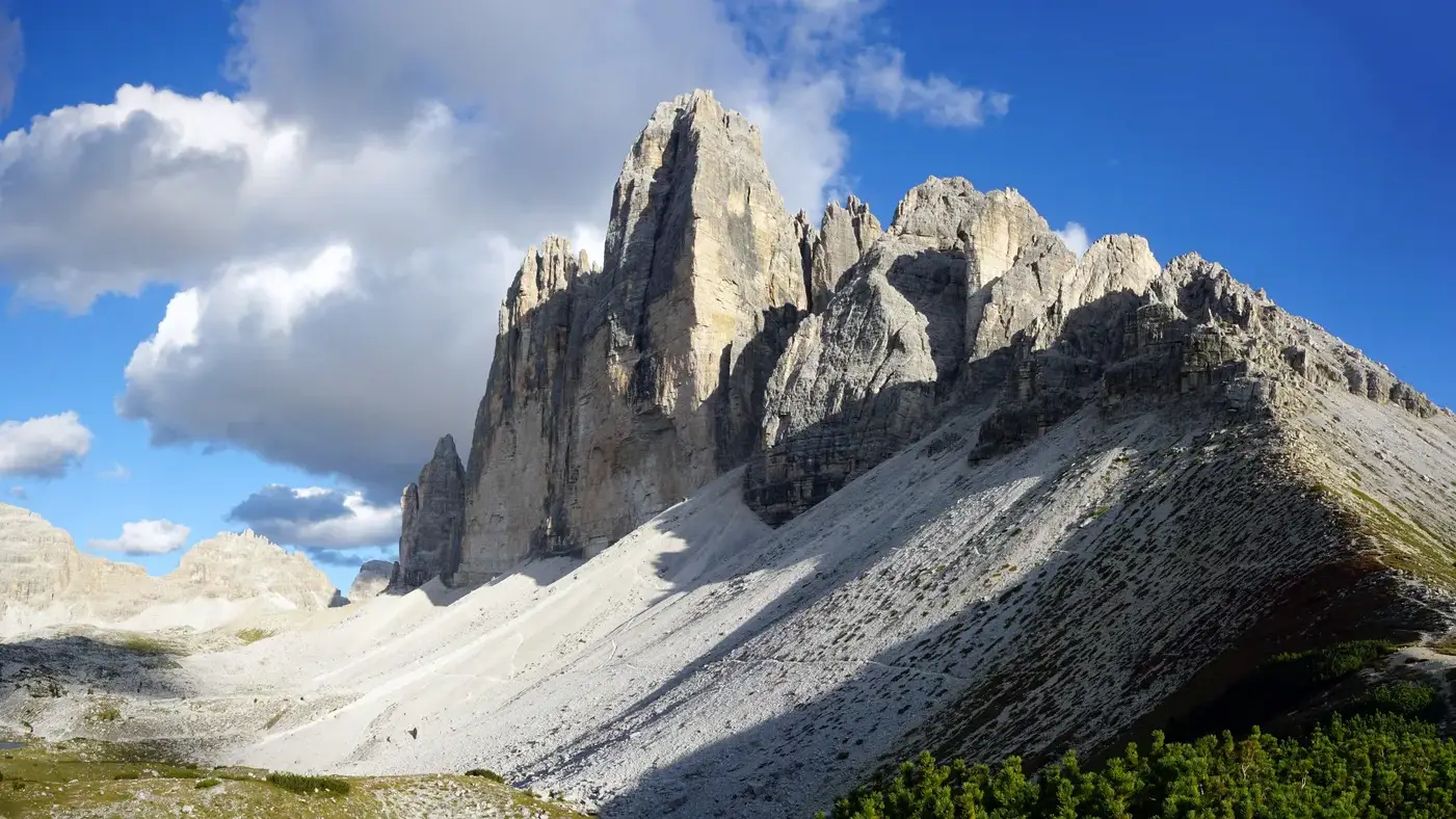Tre Cime di Lavaredo acima das encostas rochosas e do vale.