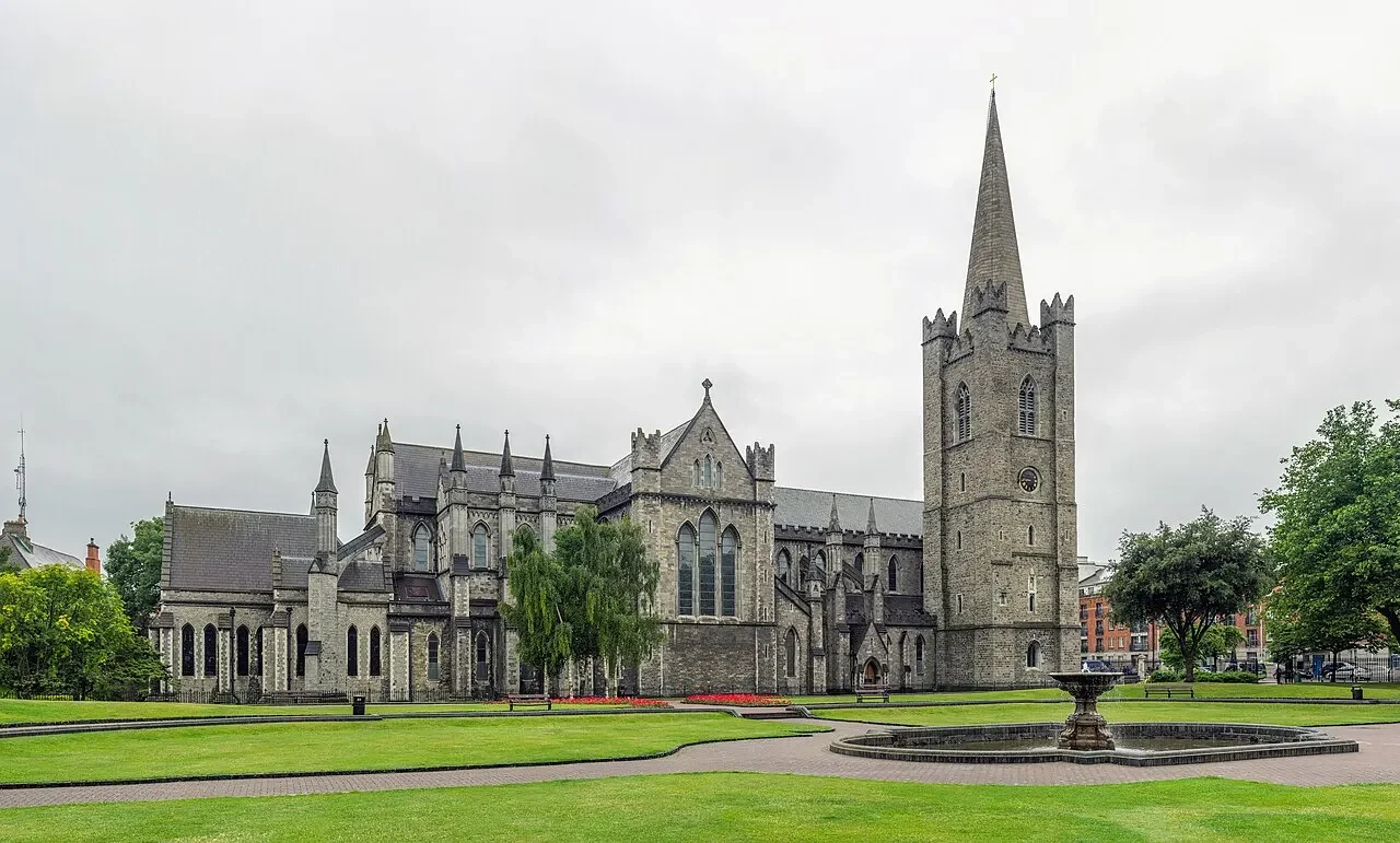 Catedral de São Patrício, em Dublin, com a torre de agulha e a nave de pedra, vista do parque ao lado.