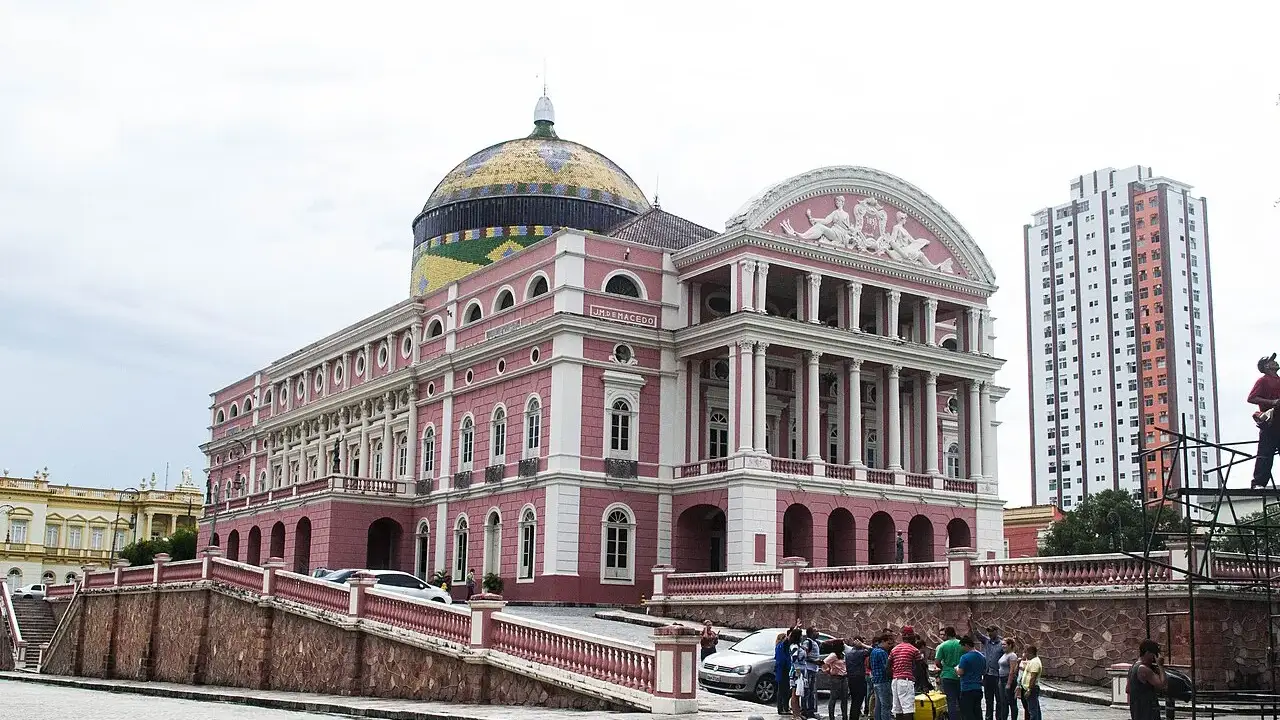 Teatro Amazonas, em Manaus, com a fachada rosa e a cúpula de telhas coloridas, visto da praça.