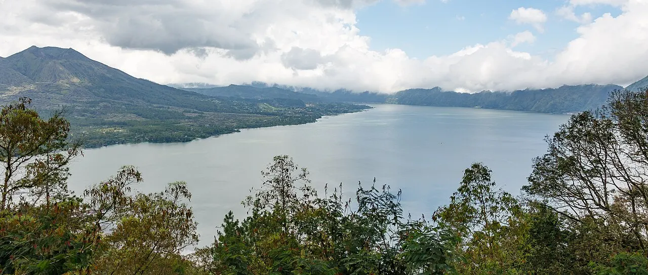 Vista do mirante sobre o lago da caldeira, com o cone do Batur à esquerda e mata no primeiro plano.