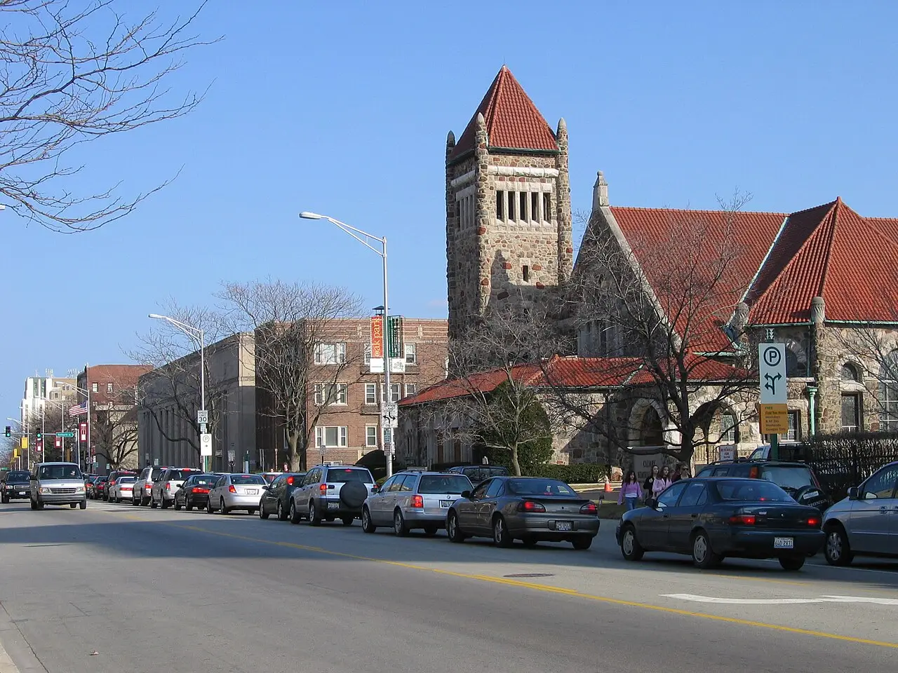 Lake Street à Oak Park, avec des voitures garées le long de la rue et une église de pierre à clocher et toit de tuiles rouges à droite.